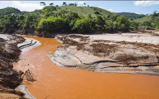 Aliran runoff berwarna cokelat membawa sedimen dari area tambang dan menyebabkan erosi permukaan tanah.